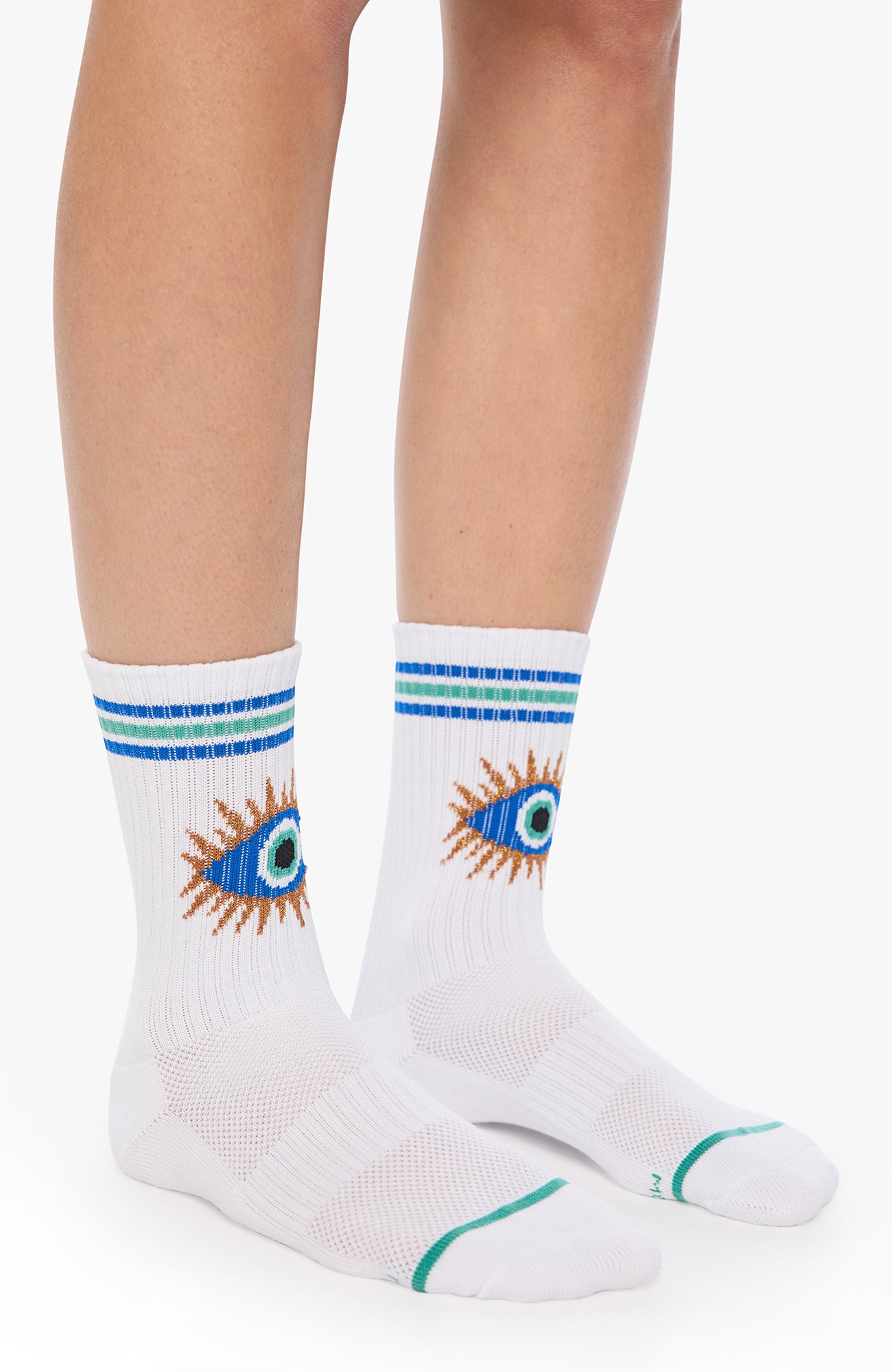 White crew socks worn on a person's feet, featuring a blue and orange eye design with a sunburst on the side and blue and green stripes near the cuff.
