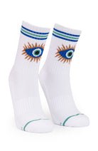 A pair of white crew socks featuring a stylized embroidered eye design in blue, green, and brown on the upper calf, with blue and green stripes at the ribbed cuff and a thin green line near the toe.