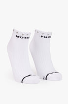 A pair of white low-cut athletic socks with black text reading 'MOTH' and 'FUCK' on the tops, plus black trim on the toes, shown on a light gray background.