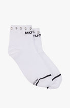 A pair of white ankle socks with black text reading 'MOT FUC' on the cuff, silver metal grommets along the top edge, and a black stripe detail near the toe, shown on a light gray background.