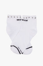 A pair of white crew socks with black text reading 'MOKER' and 'Wear you' on the sole, decorated with silver metal studs along the top cuff.