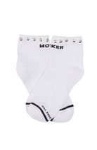 A pair of white crew socks with black 'MOKER' branding on the top cuff, decorated with silver metal studs, and black trim on the toes.