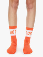 Orange socks with 'HOT DOG' text worn by a person on a white background