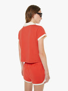 Woman wearing a red outfit with white trim on a white background