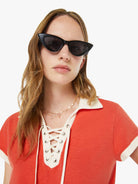 Woman wearing a red outfit with a white collar and black cat-eye sunglasses on a white background