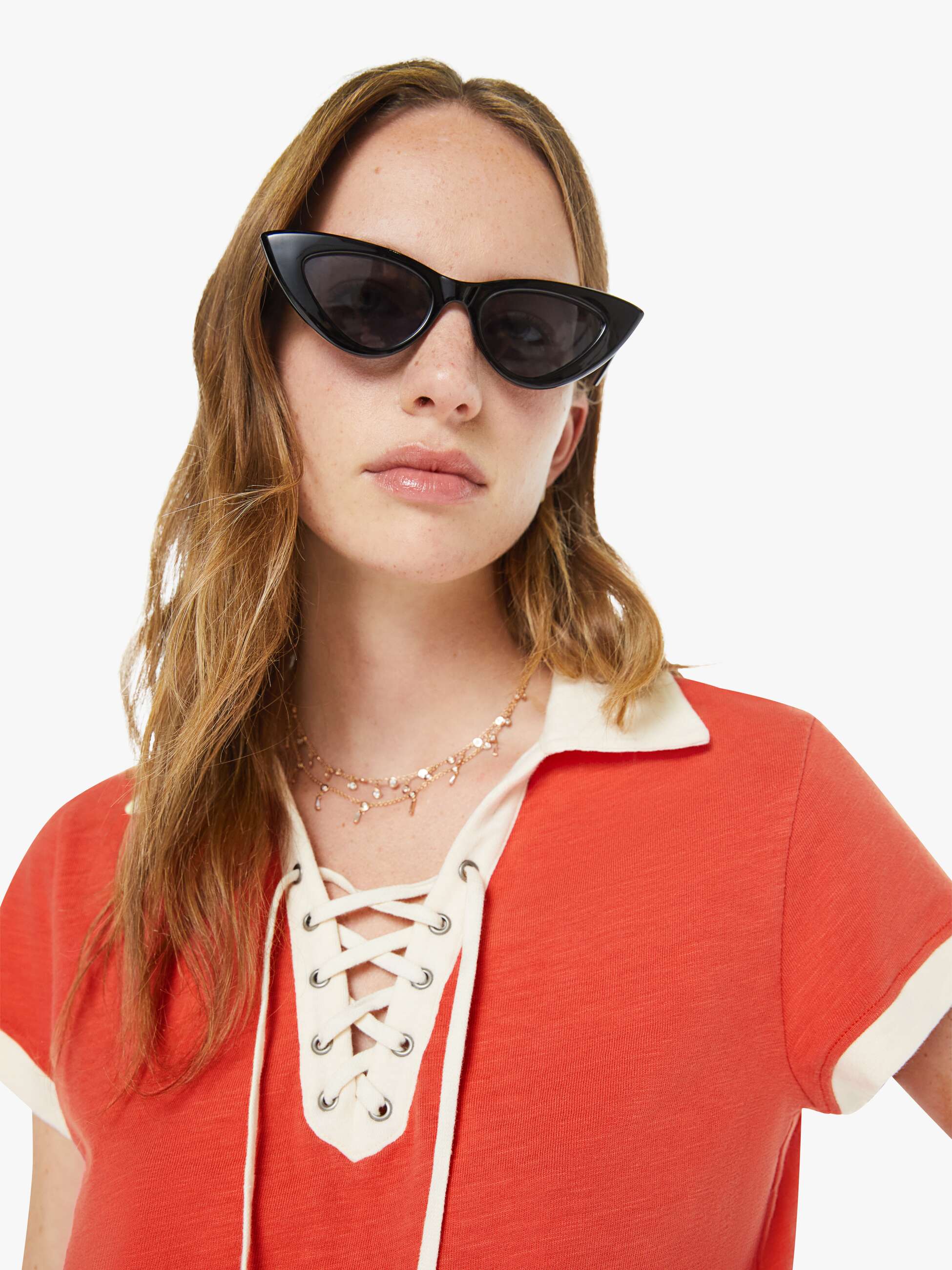 Woman wearing a red outfit with a white collar and black cat-eye sunglasses on a white background