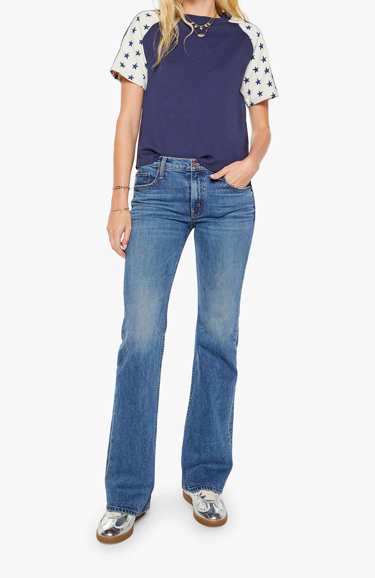 Person wearing a navy blue baseball shirt with white sleeves and blue jeans on a white background