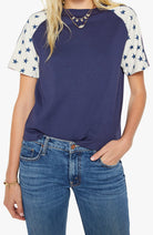 Person wearing a navy blue t-shirt with star-patterned sleeves and blue jeans on a white background