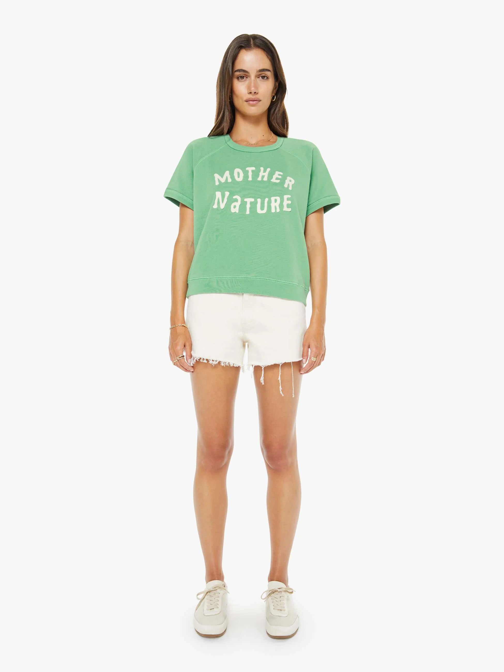 Woman wearing a green 'Mother Nature' t-shirt and white shorts on a white background
