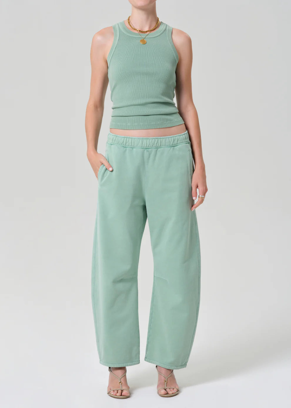 Person wearing a mint green sleeveless top and pants on a white background