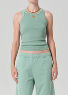 Person wearing a matching mint green tank top and pants set on a light gray background