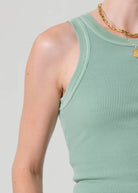 Person wearing a light green ribbed tank top on a plain background