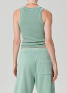 Person wearing a matching mint green tank top and pants on a light gray background