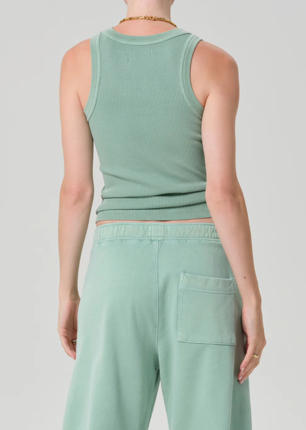 Person wearing a matching mint green tank top and pants on a light gray background