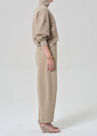 Person wearing a beige hoodie and pants on a white background