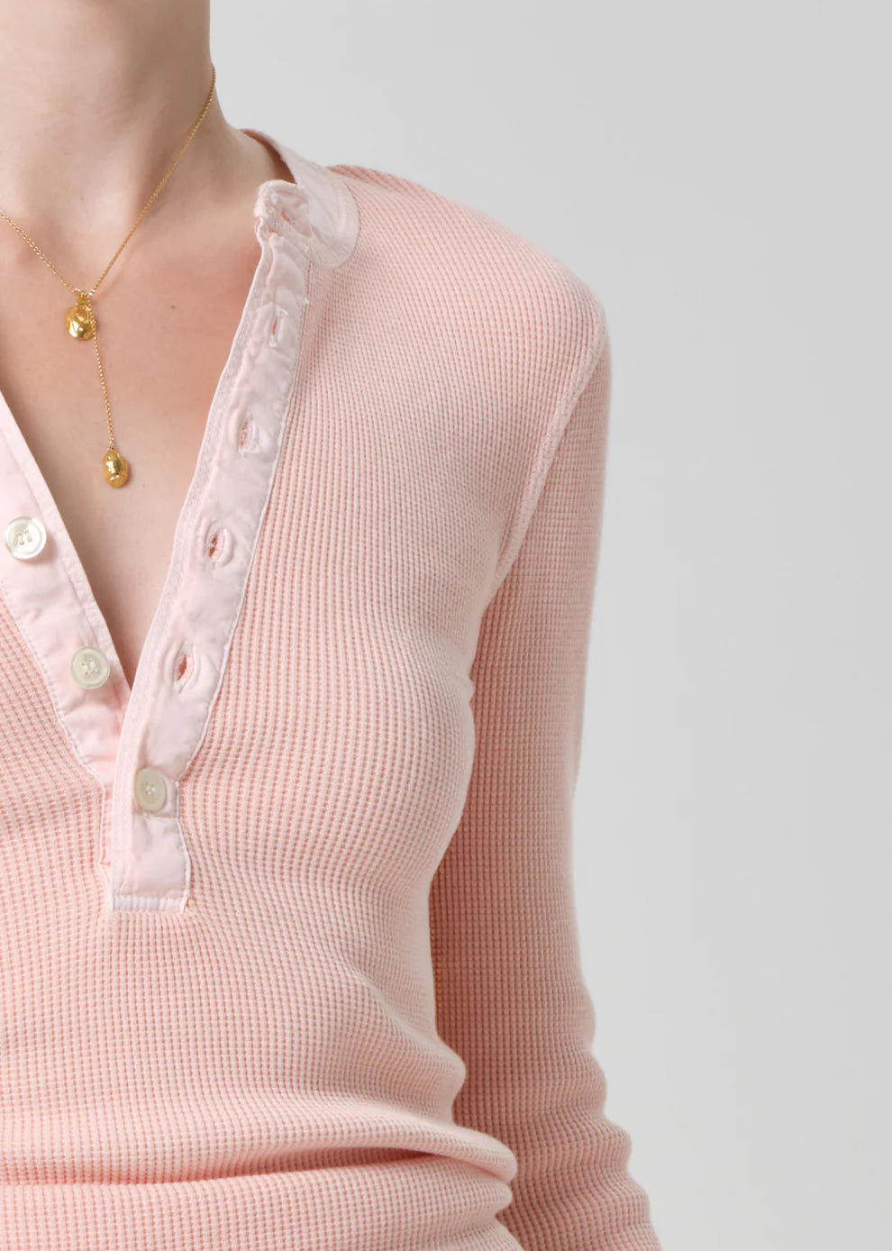 Close-up of a pink ribbed sweater with lace trim on a plain background