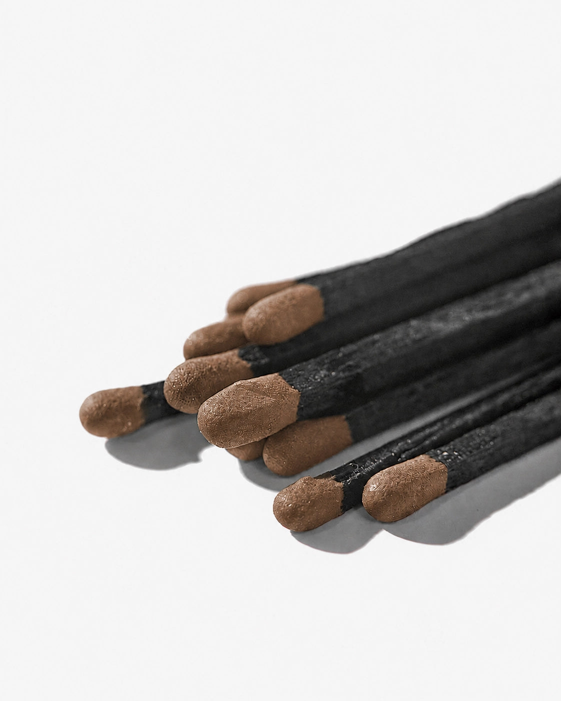 Set of black matches with brown tips on a white background