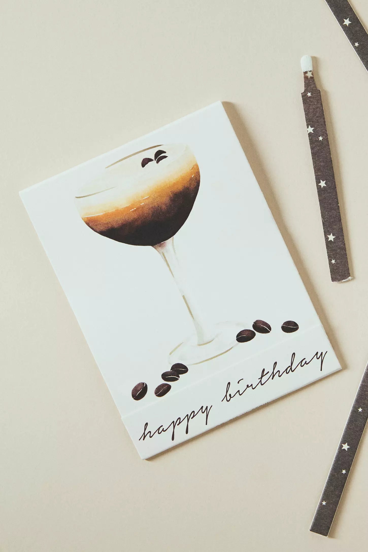 Greeting card with a coffee-themed design and 'happy birthday' text, accompanied by a pen on a beige background.