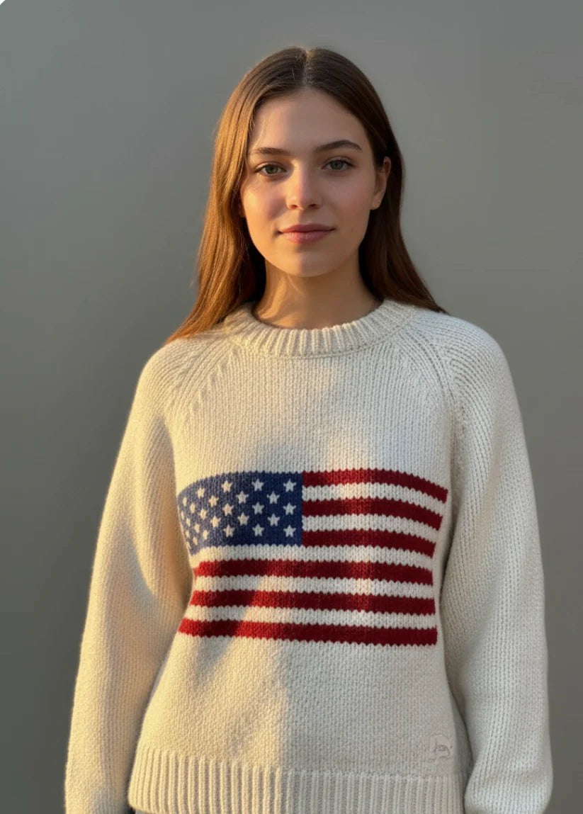Person wearing a cream sweater with an American flag design against a gray background
