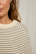 Close-up of a person wearing a striped sweater with a neutral background