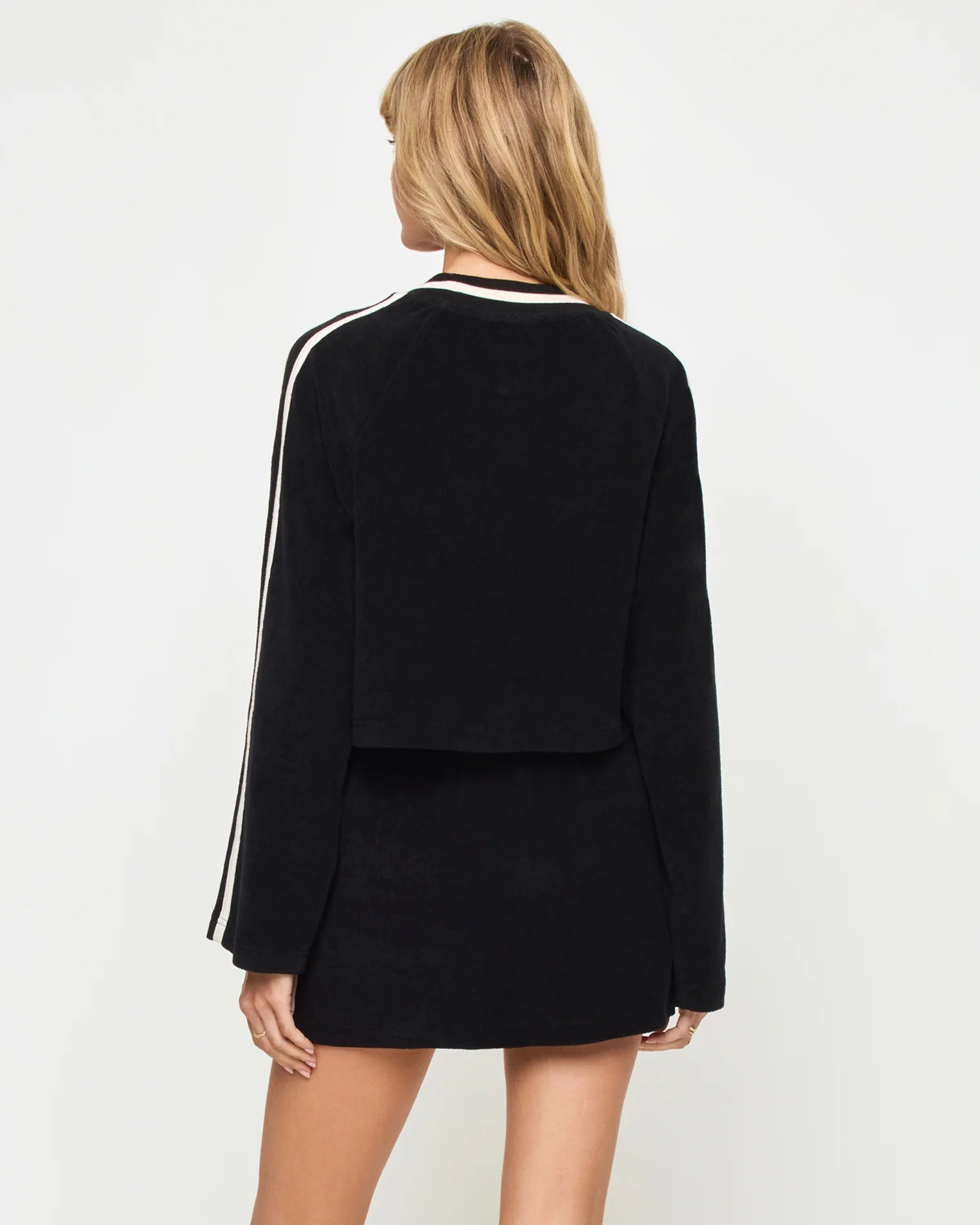 Black outfit with white stripes on sleeves against a plain background