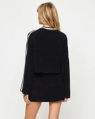 Black outfit with white stripes on sleeves against a plain background