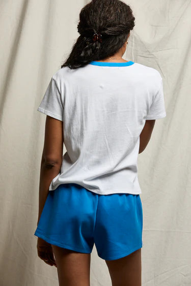 Person wearing a white t-shirt and blue shorts against a plain background