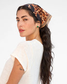 Woman wearing a leopard print headscarf with a white background