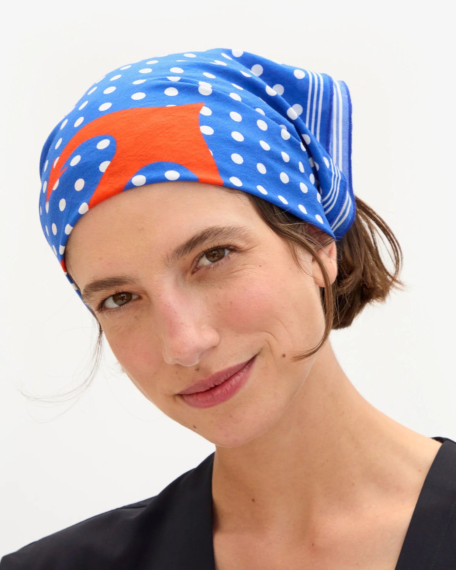 Woman wearing a colorful headscarf with polka dots and stripes on a white background