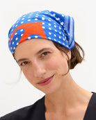 Woman wearing a colorful headscarf with polka dots and stripes on a white background
