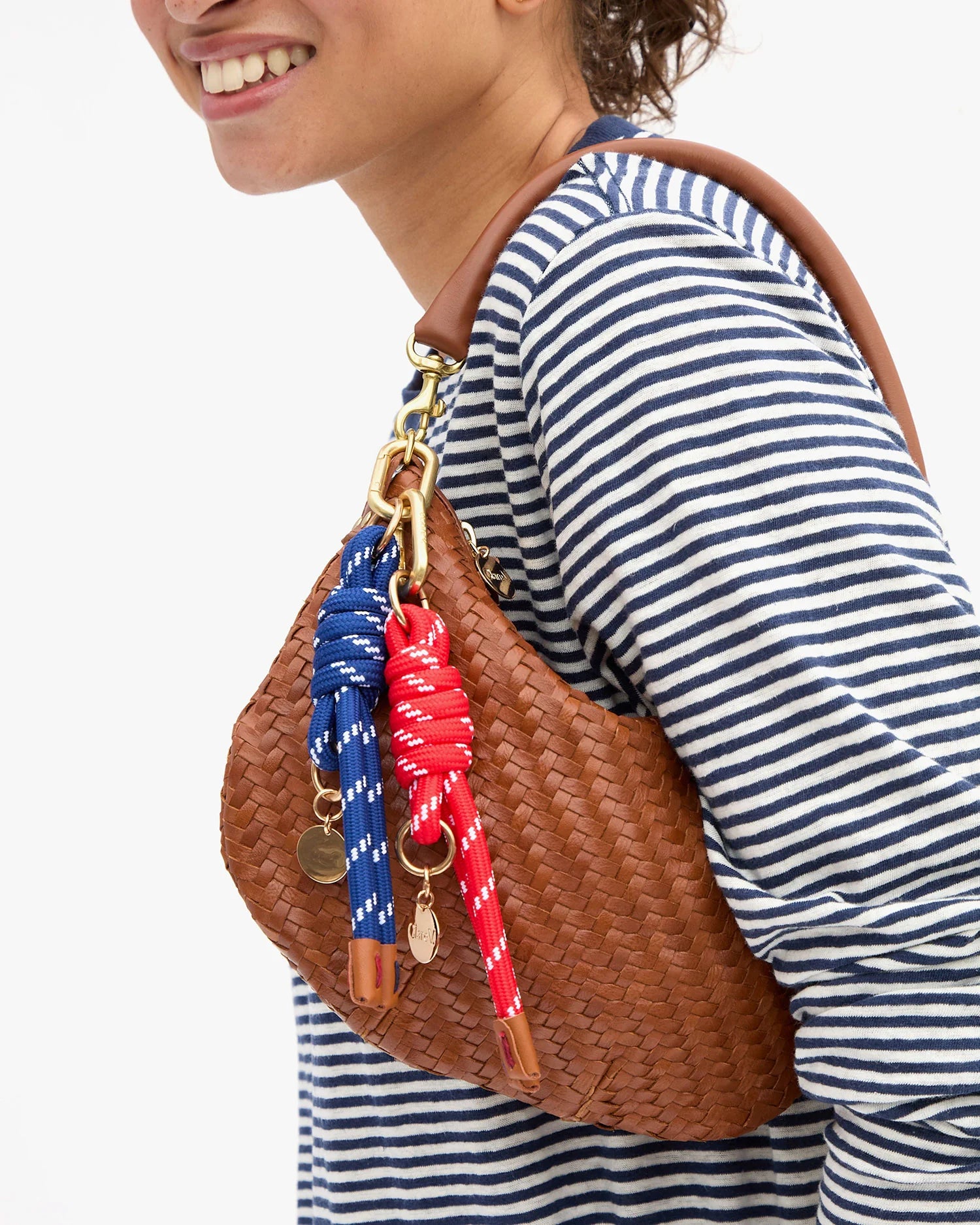 Person wearing a striped shirt with a brown woven handbag featuring colorful straps.