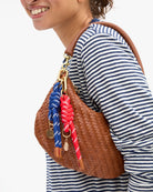 Person wearing a striped shirt with a brown woven handbag featuring colorful straps.