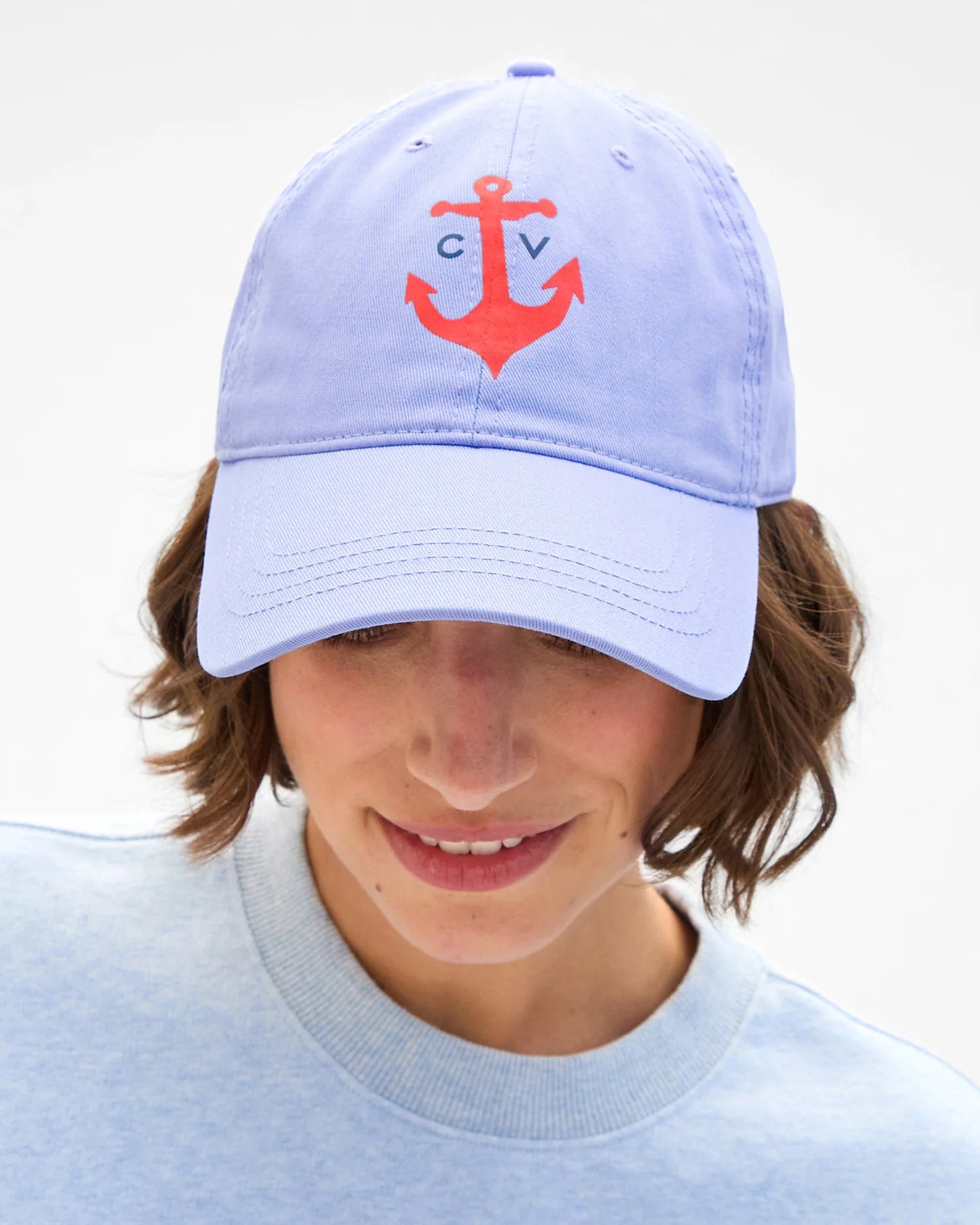 Light blue cap with red anchor design worn by a person on a white background