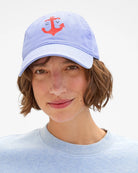 Person wearing a light blue cap with a red anchor design on a white background