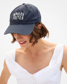Person wearing a navy blue cap with 'Moules Frites' text on a white background