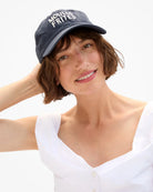 Woman wearing a navy blue cap with 'Moules Frites' text on a white background