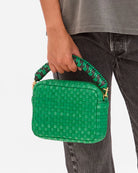 Green woven handbag held by a person against a white background