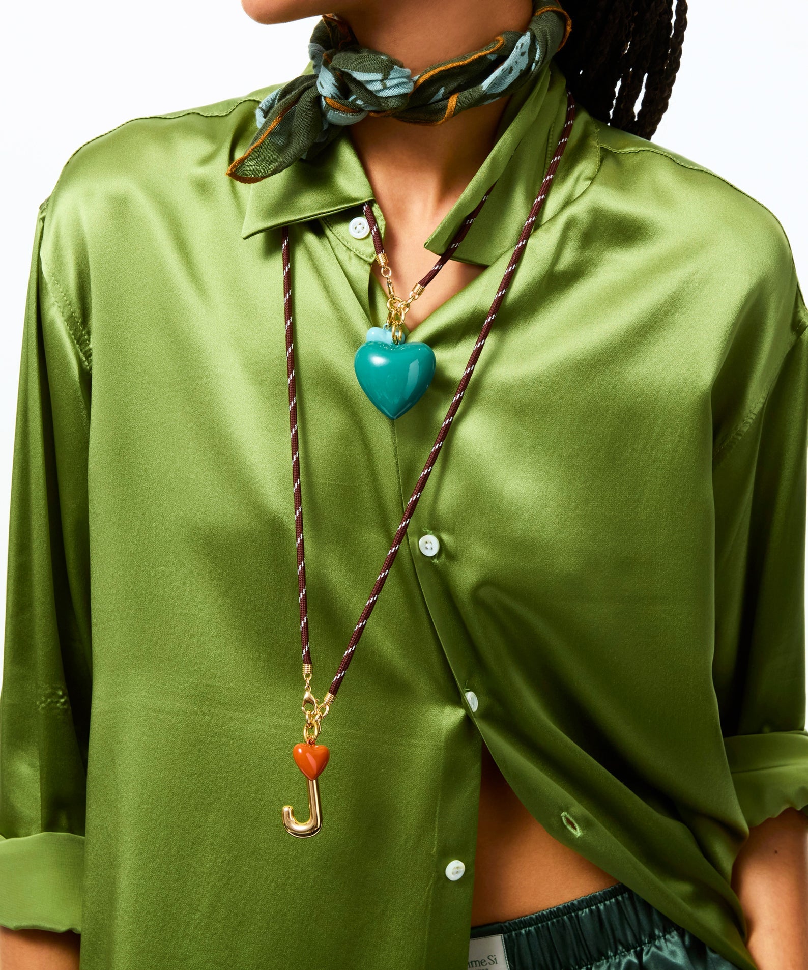 Person wearing a green shirt with a colorful scarf and necklace.
