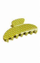 A glossy yellow-green claw hair clip decorated with white polka dots, shown on a plain white background.