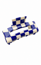 A glossy checkered hair claw clip with alternating royal blue and off-white squares, shown on a plain white background.