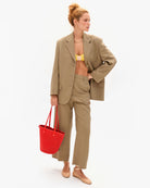 Woman in beige suit holding a red bag on a white background