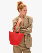 Woman holding a red handbag against a white background
