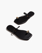 Pair of black sandals with gold accents on a white background