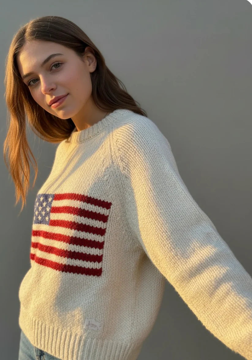 Woman wearing a cream sweater with an American flag design against a neutral background