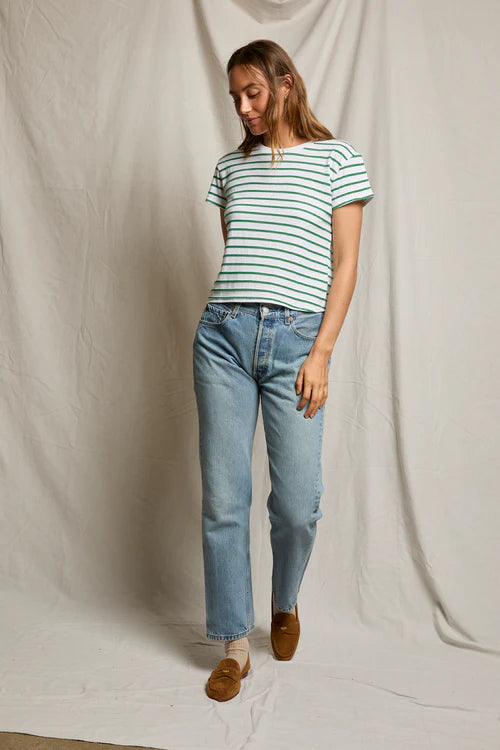 Woman wearing a striped shirt and jeans standing against a plain background