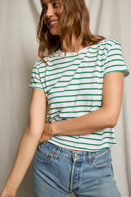 Woman wearing a green and white striped shirt with blue jeans against a plain background