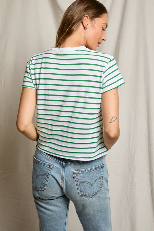 Person wearing a green and white striped t-shirt and blue jeans against a neutral background