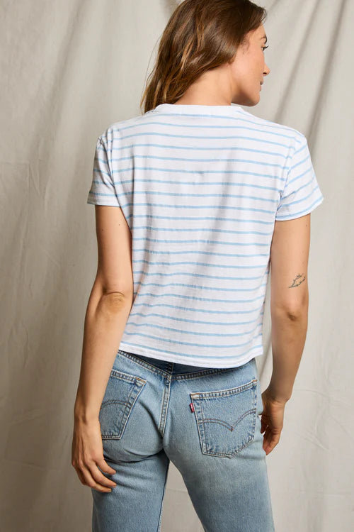 Person wearing a striped shirt and jeans against a neutral background
