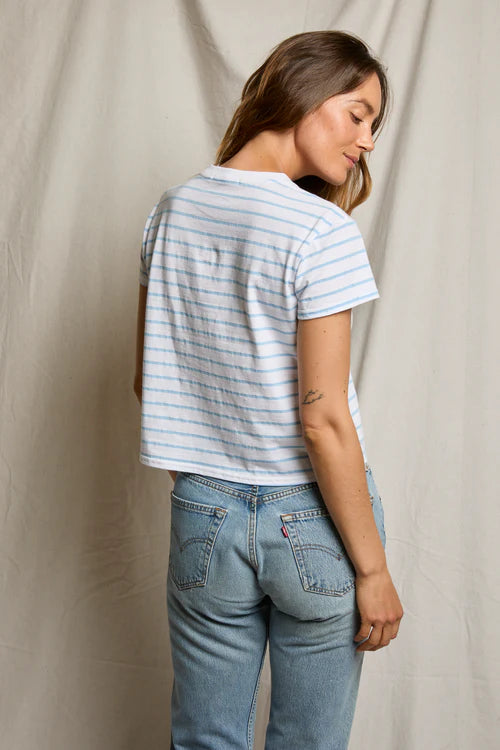 Woman wearing a striped shirt and jeans against a plain background