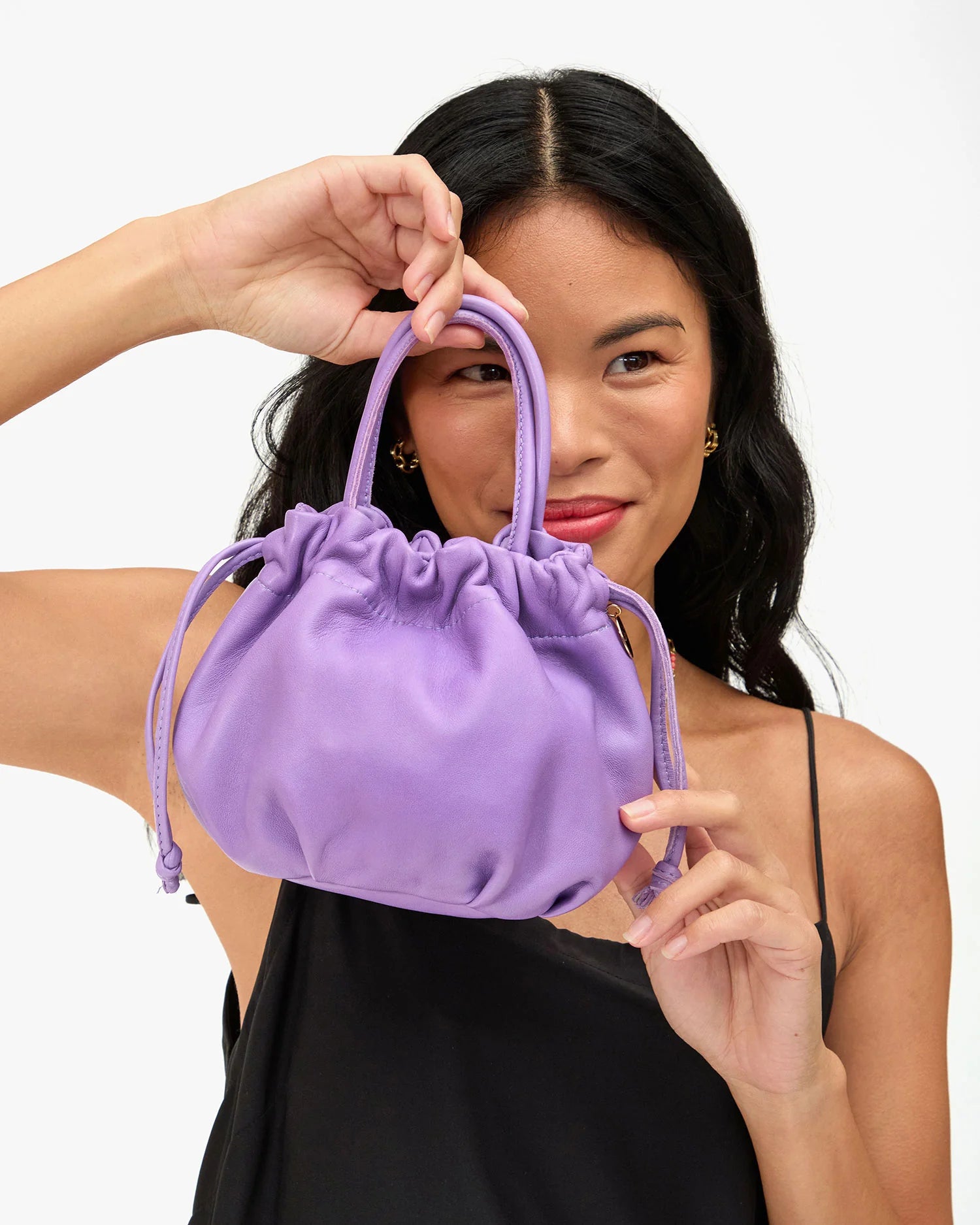 Woman holding a purple drawstring bag against a white background